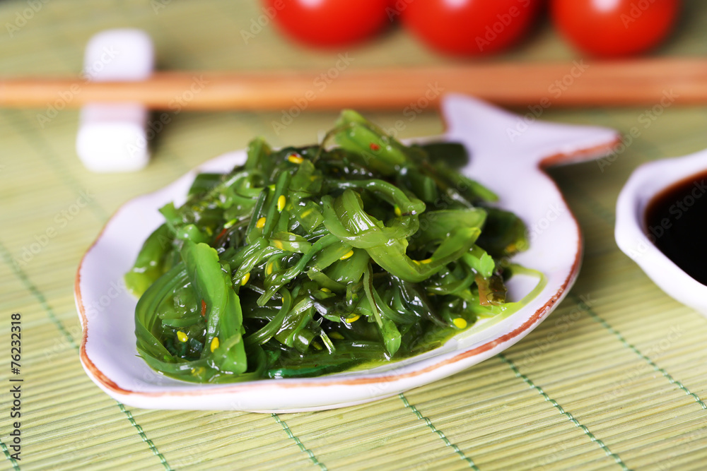 Seaweed salad in plate on bamboo mat background Seaweed salad in plate on bamboo mat background