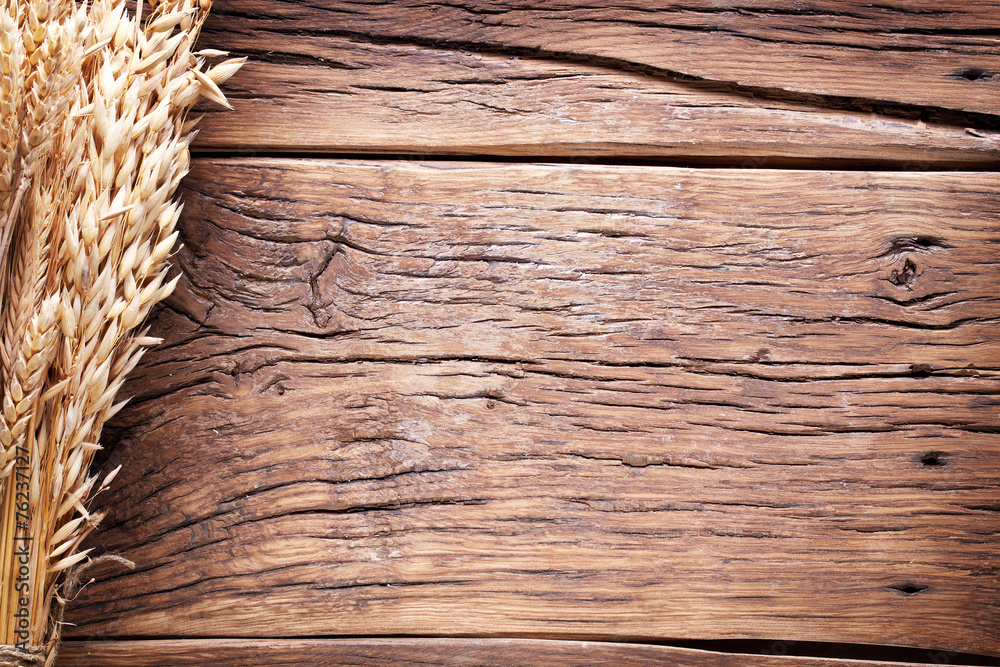 Fototapeta premium Ears of wheat on old wooden table.