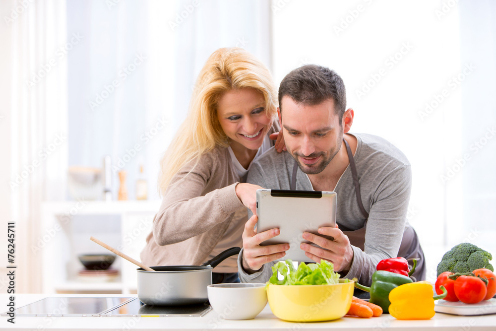 Young attractive couple reading recipe on a  tablet