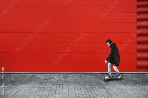 Obraz na plátne Guy rides his skate in front of red wall