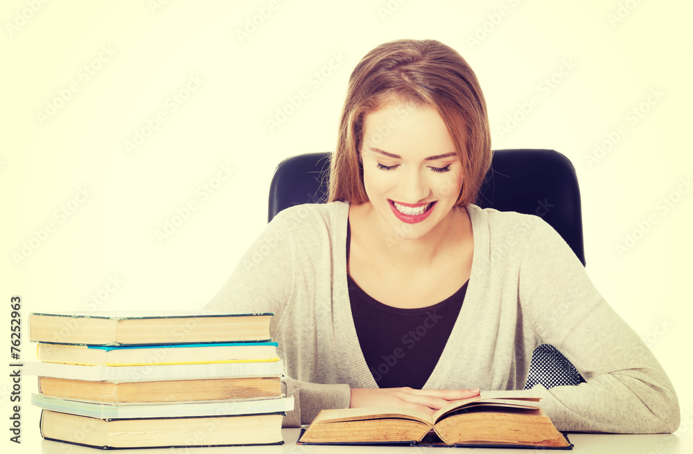 Student woman sitting by the desk with books. Student woman sitting by the desk with books.