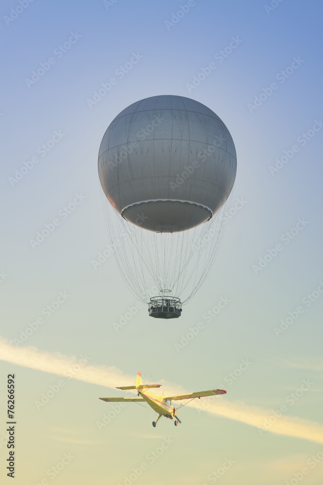 Obraz premium Gas Balloon and Yellow Aircraft against the Sky