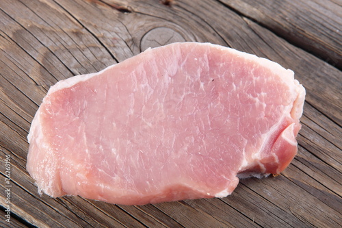 Raw pork chops on wooden cutting board.