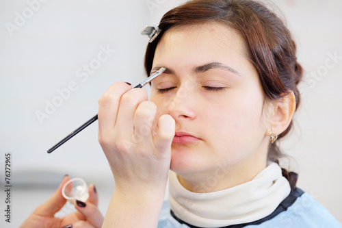 Makeup artist stylist applying with brush cosmetic on eyebrow