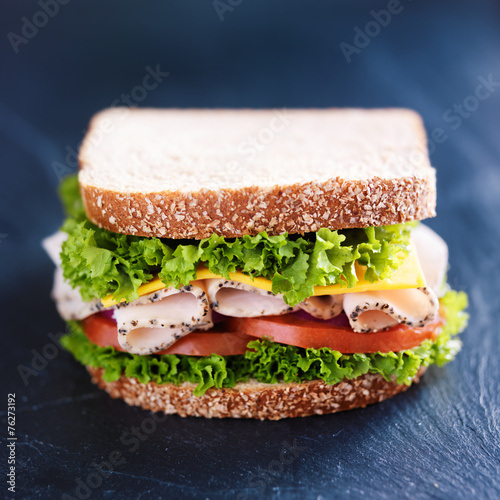 deli meat turkey sandwich on slate surface