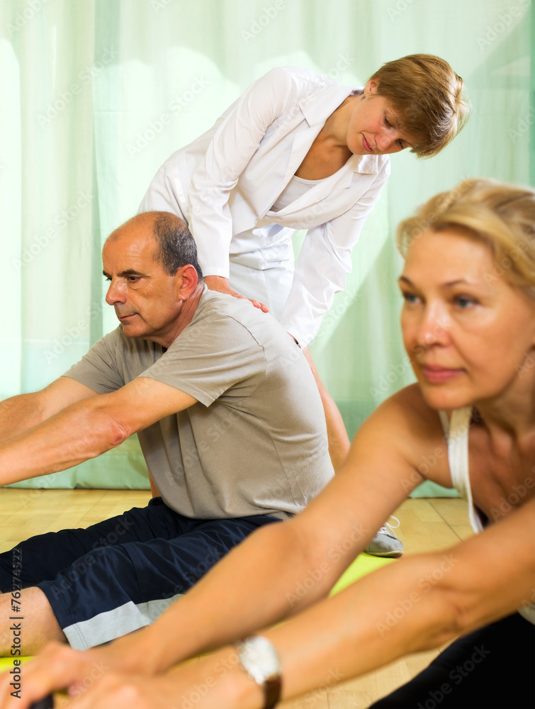 Obraz premium Yoga instructor showing asana to mature couple
