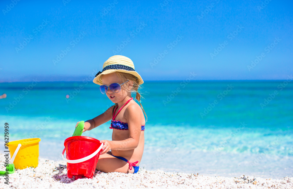 Adorable little girl playing with beach toys during tropical Adorable little girl playing with beach toys during tropical