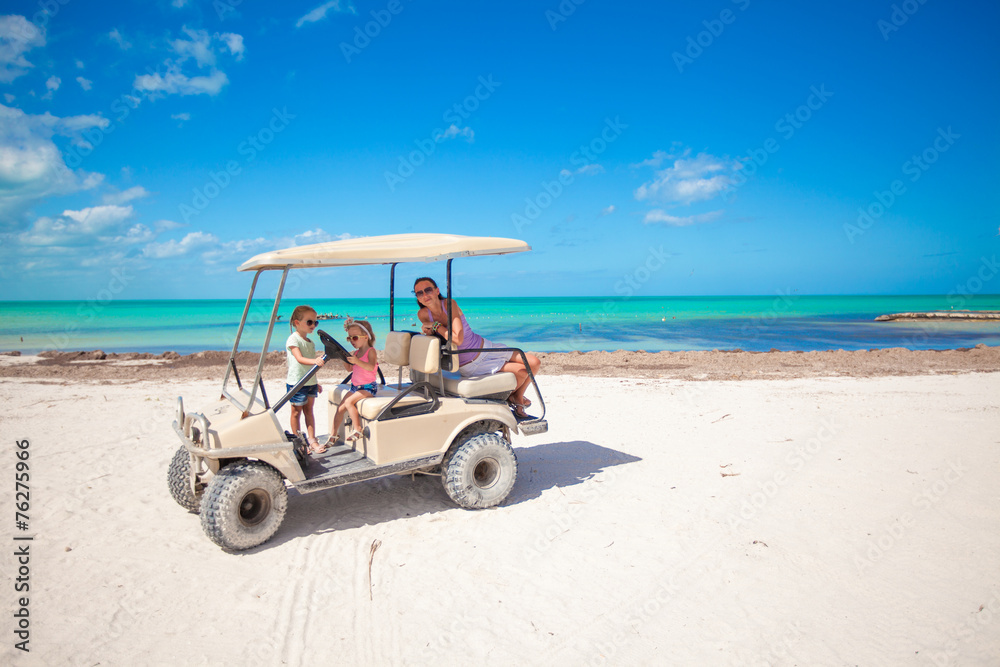 Little girls and their mother driving golf cart at tropical