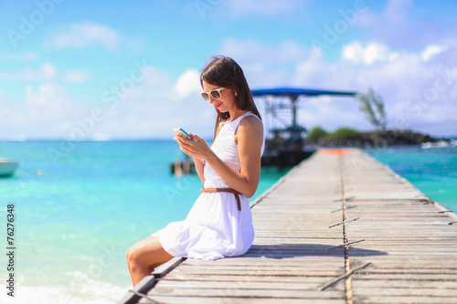Obraz na płótnie Young woman talking on phone during tropical beach vacation w salonie