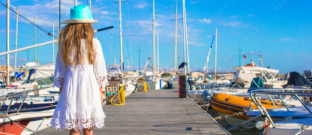 Adorable little girl have fun in a port on summer day