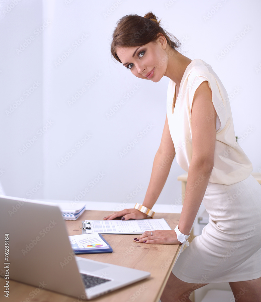 Obraz premium Attractive young businesswoman standing near desk with folder in