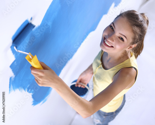 Happy beautiful young woman doing wall painting  standing on