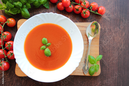 Obraz na plátně Plate with tomato cream soup on wooden board
