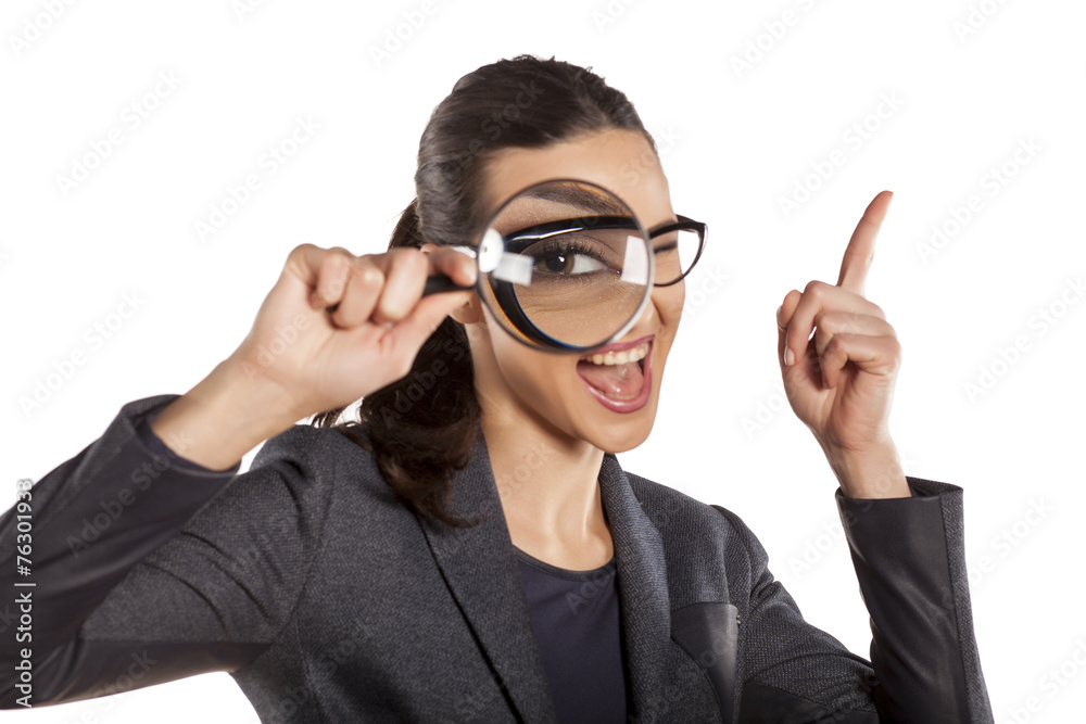 young woman looking through a magnifying glass and pointing up young woman looking through a magnifying glass and pointing up