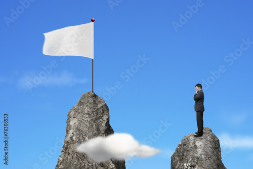 Quadro su tela Businessman standing on peak with blank white flag and sky
