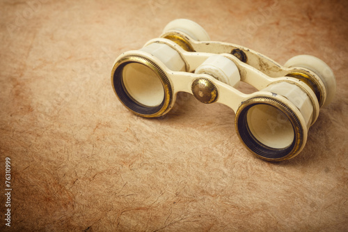 Old binoculars on vintage paper background