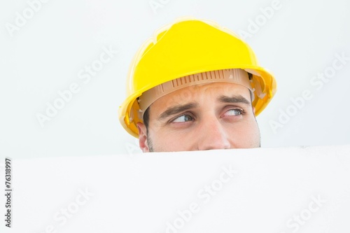 Repairman looking away while in front of billboard