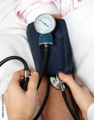 Doctor checking blood pressure with stethoscope photo