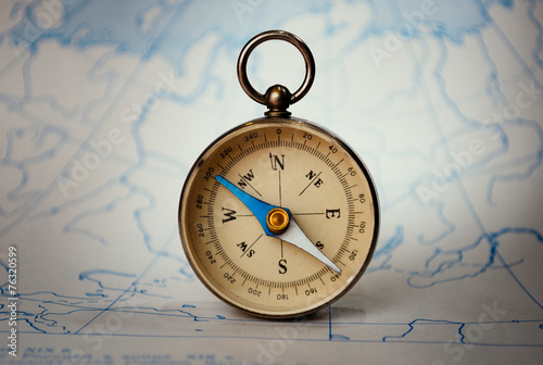 Magnetic compass standing upright on a map