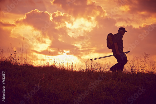 Wanderer mit Cap und Stöcken bergab