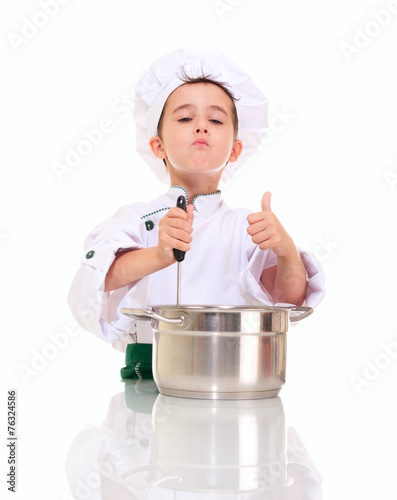 Little satisfied boy chef with ladle stirring in the pot