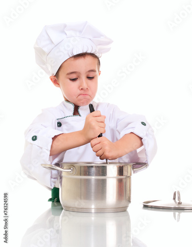 Little boy chef with ladle stiring in the pot by both hands