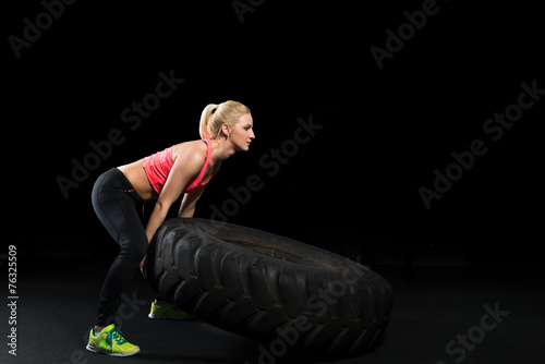 Muscular woman use big tire as part of Crossfit Training