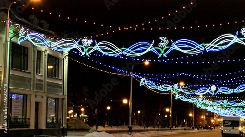 Festively decorated night street with the passing cars