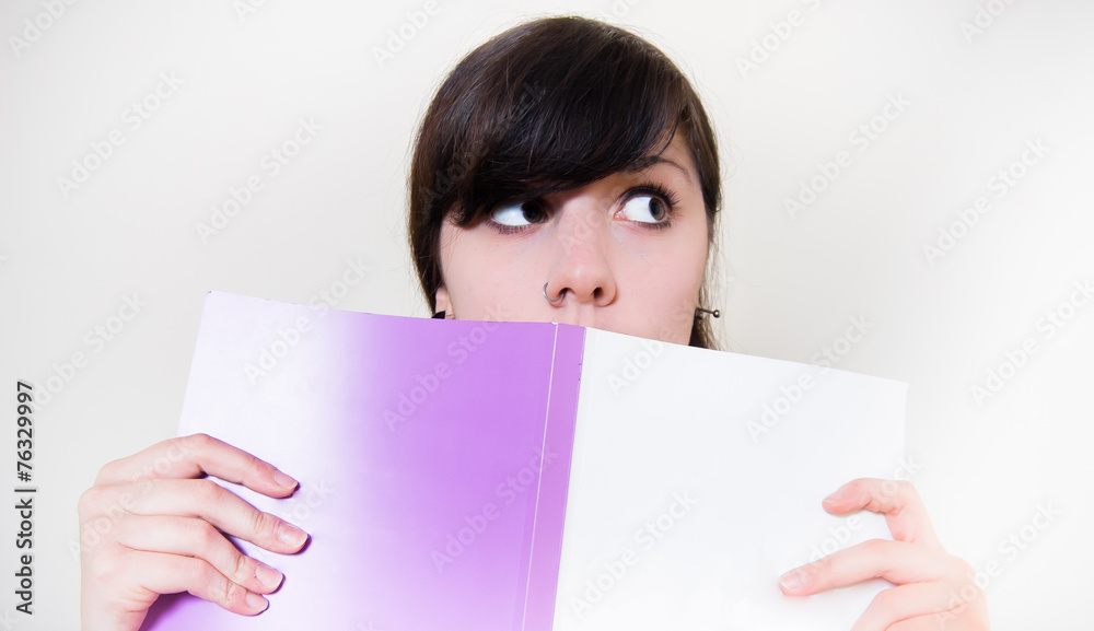 Young brunette girl reading a book and looking out Young brunette girl reading a book and looking out
