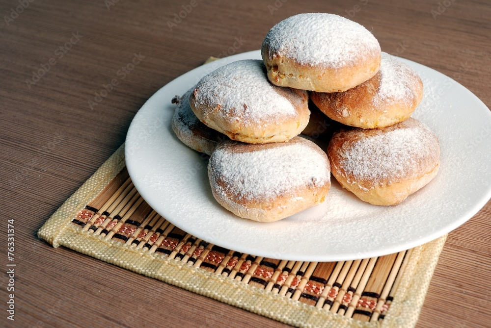 Bun with powdered sugar on a wooden table