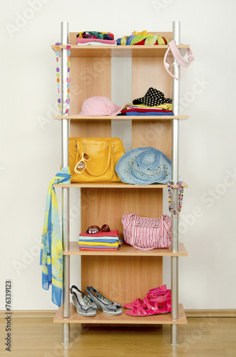 Tidy wardrobe with summer clothes nicely arranged on a shelf. 