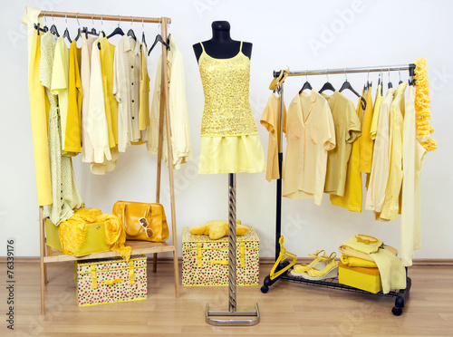 Dressing closet with yellow clothes on hangers and dummy.