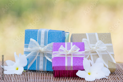 Colorful gift boxes  on wooden mat on meadow background photo