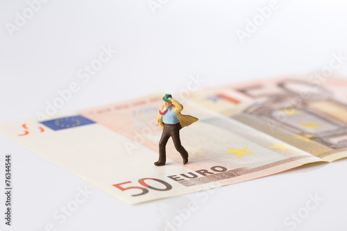 Fototapeta Naklejka Na Ścianę i Meble -  businessman figurine running on a euro banknote