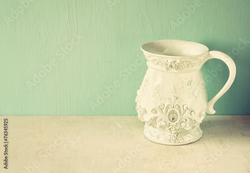 white classic and antique vase on wooden table. filtered image