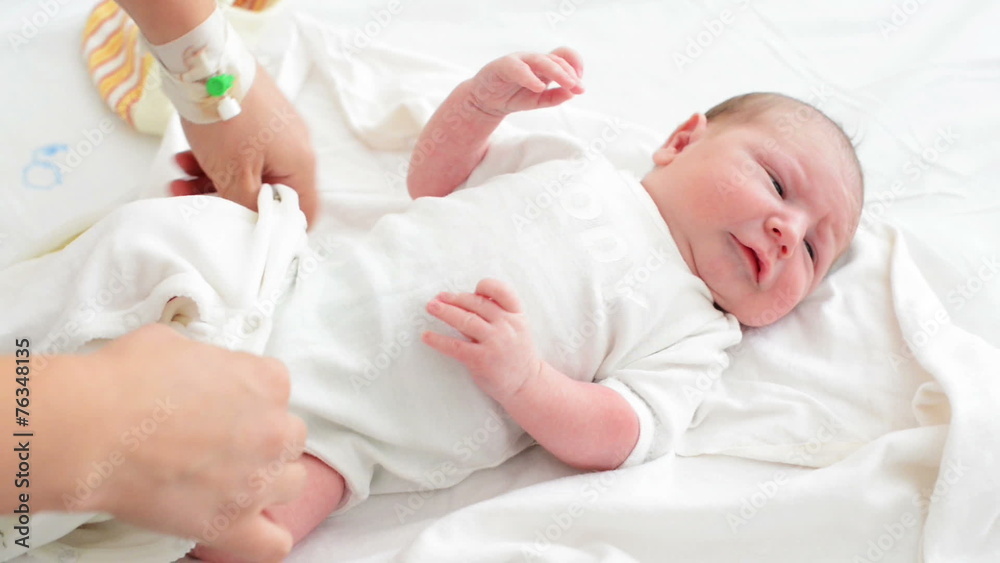Nursing mother dressing her newborn baby in maternity Nursing mother dressing her newborn baby in maternity