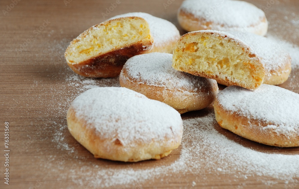 Bun with powdered sugar on a wooden table