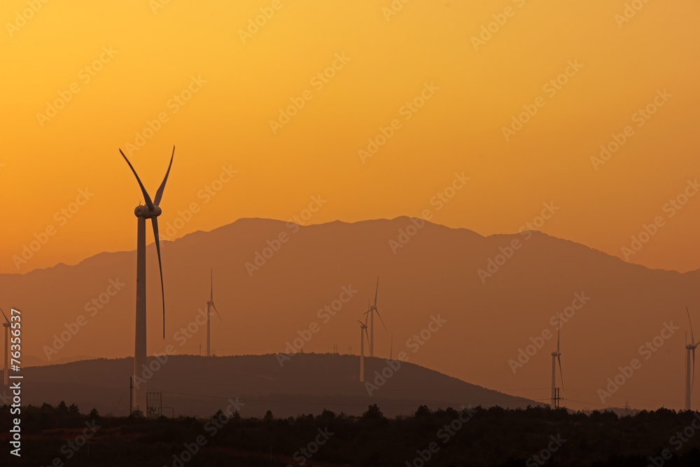 Obraz premium Wind turbines with power line in the sunset
