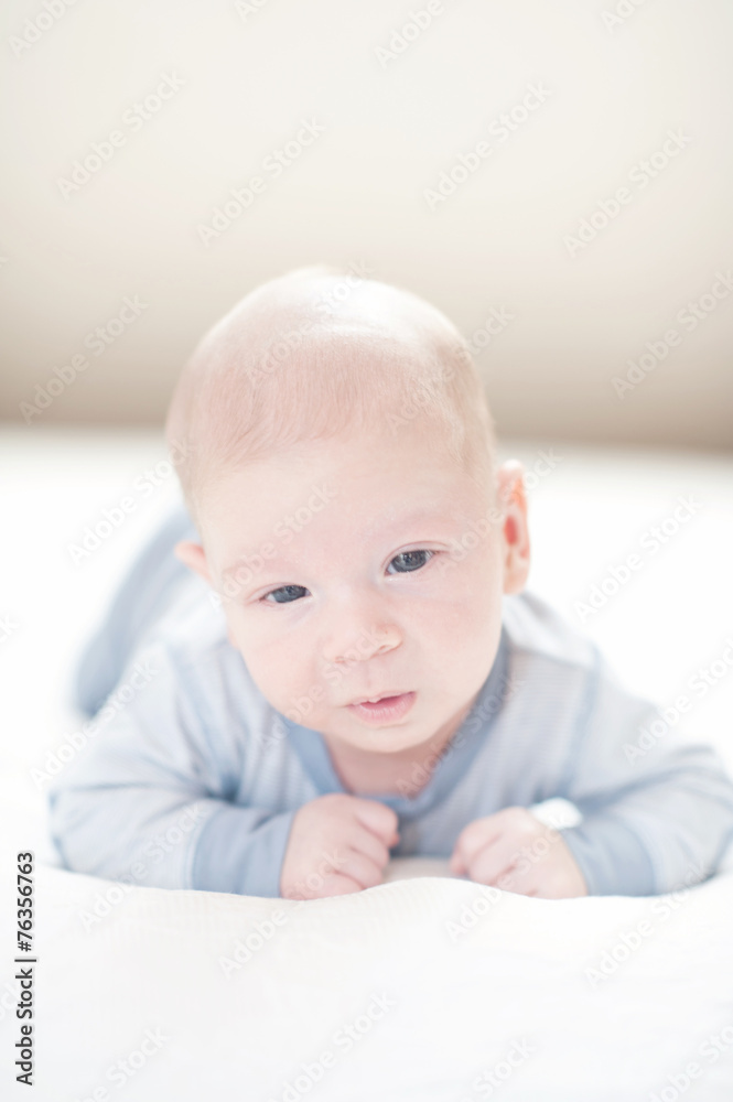 Charming newborn baby boy in blue on a bed