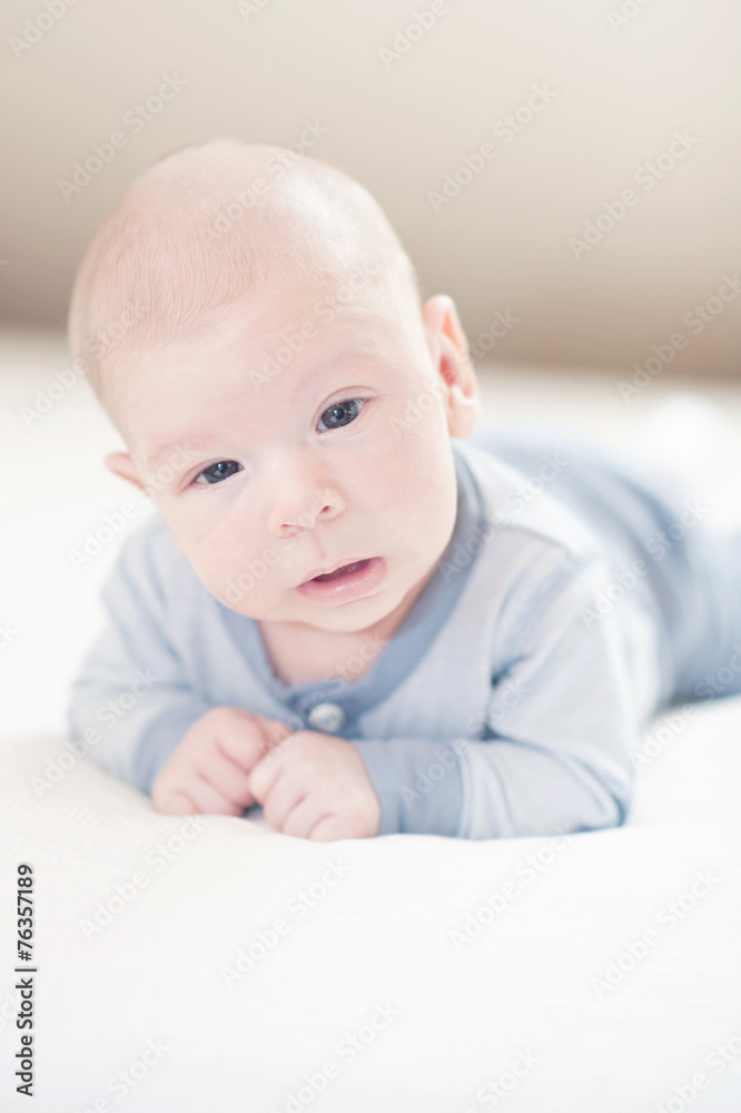 Lovely, cute newborn baby boy in blue on a bed