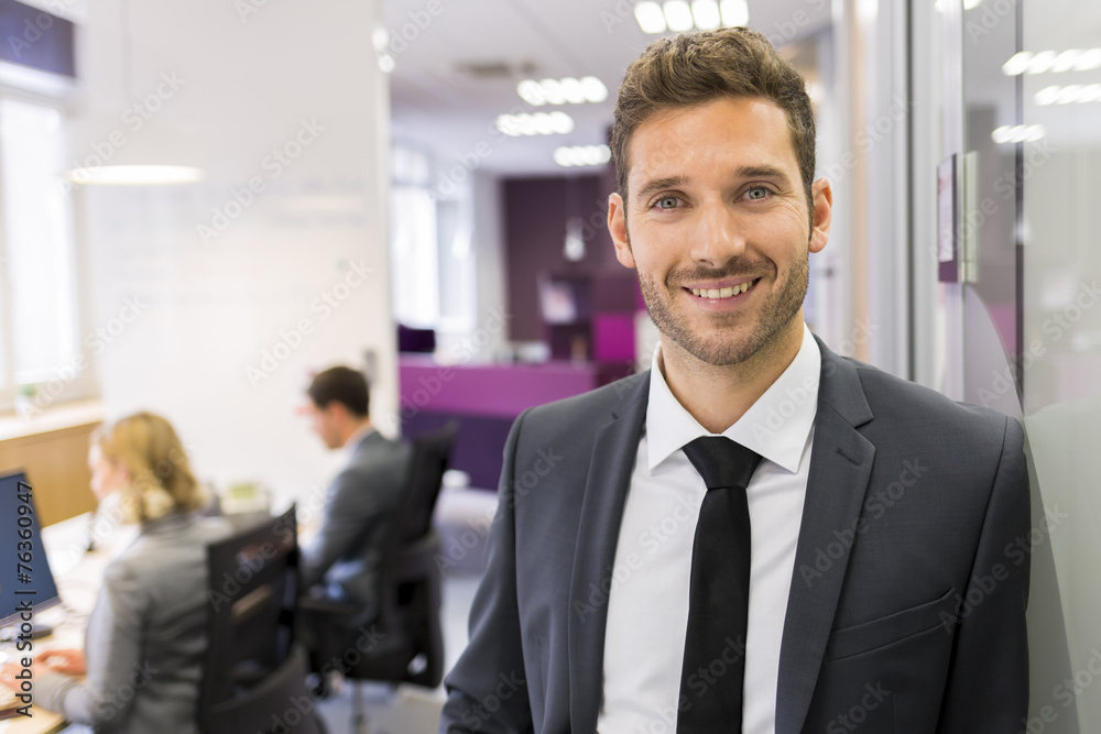 Portrait of smiling Businessman posing in modern office, lookin Portrait of smiling Businessman posing in modern office, lookin