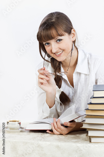 Beautiful Smiling girl reading a book on the table