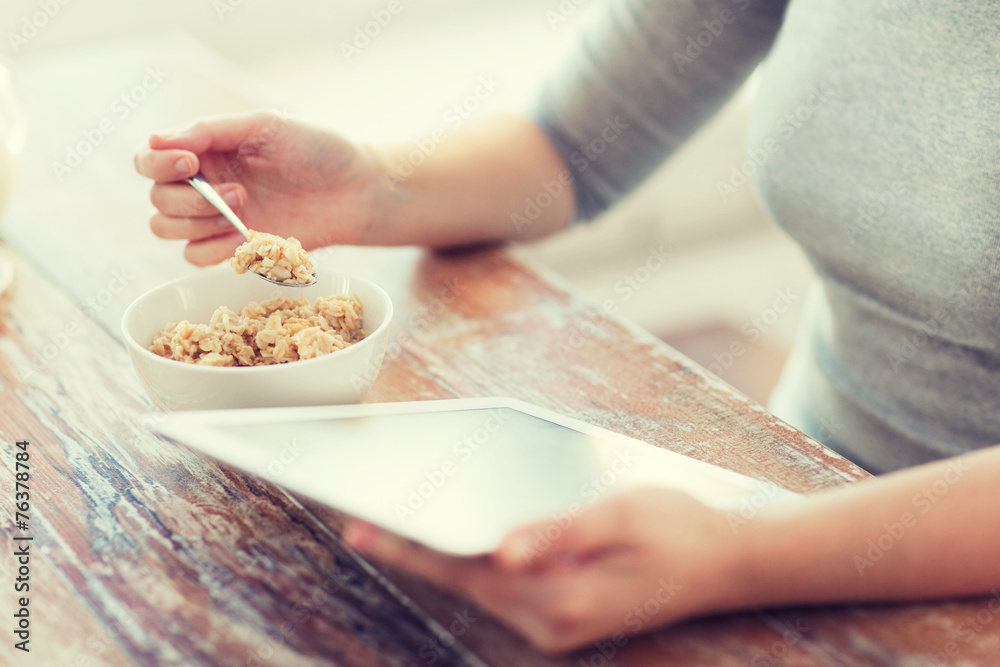 woman eating porridge and using tablet pc