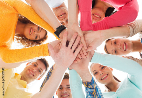 smiling teenagers with hands on top of each other