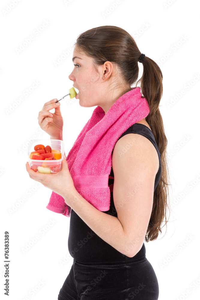 Young woman in sports wear with towel eating fresh fruit