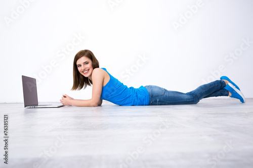 Portrait of a smiling woman lying on the floor with laptop