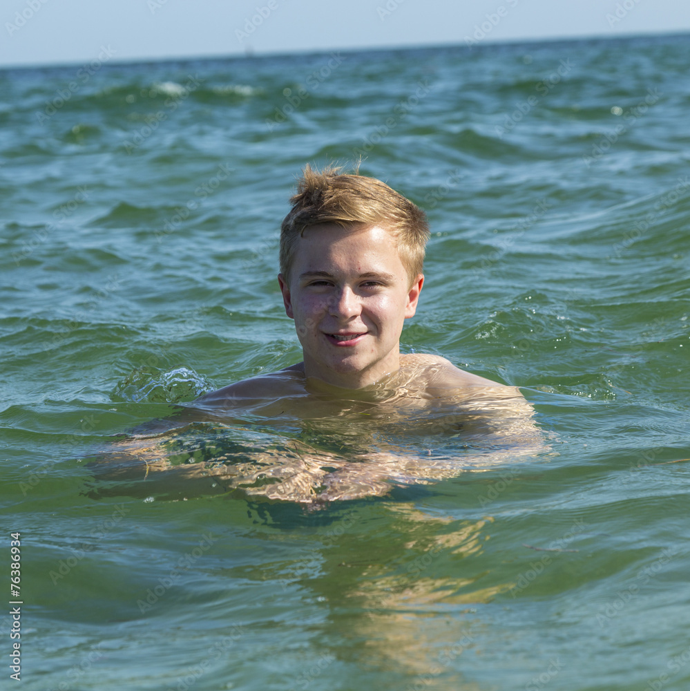 handsome teen has fun swimming in the ocean