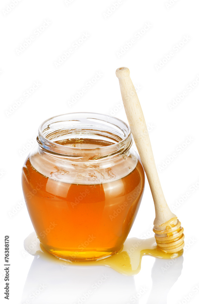 Glass jar of honey with wooden drizzler on a white background. Glass jar of honey with wooden drizzler on a white background.