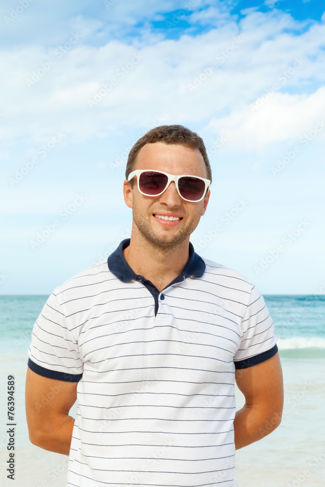Young smiling man standing on summer sea coast Young smiling man standing on summer sea coast