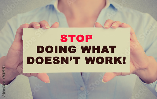 Businesswoman hands holding sign Stop Doing What Doesn't Work
